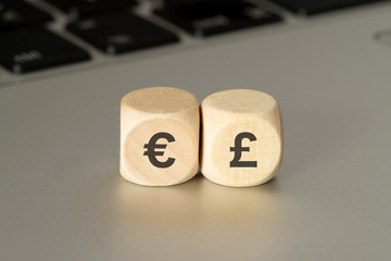 Ein Computer und Würfeln mit Symbolen für Euro und englischen Pfund