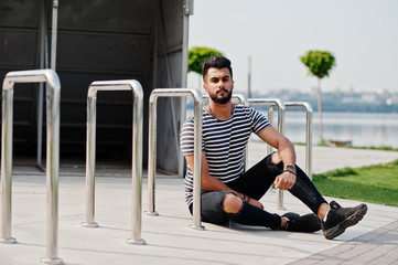 Handsome tall arabian beard man model at stripped shirt posed outdoor. Fashionable arab guy.