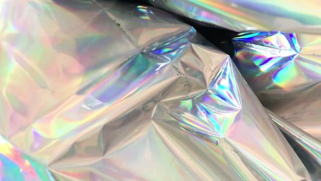 holographic Iridescent foil. Multicolor surface and shiny background with waves. Colorful holographic foil moving and changing reflection and lights.
