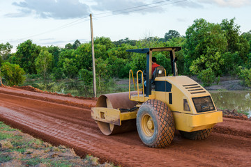 Roller steamroller or vibratory roller machine working on road construction site of new road.