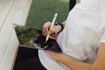 Neutral person with tablet and pen sitting at a cafe