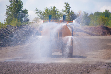 Heavy truck pours the road with water in the iron ore quarry. Dust removal, protection of the...