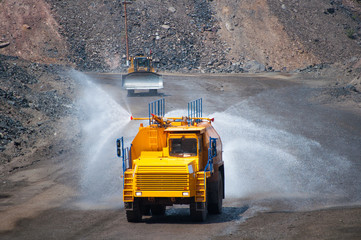Heavy truck pours the road with water in the iron ore quarry. Dust removal, protection of the environment. Irrigation of the road from dust © Yevhen
