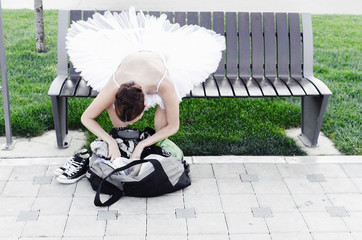 Ballerina sitting on bench in nature