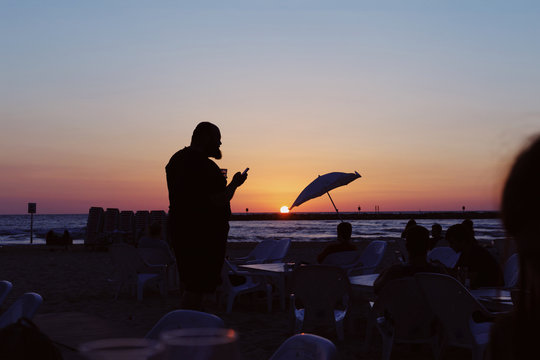 Silhouette of a man with smartphone on the beach on sunset