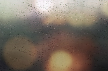 Drops of rain on window with abstract lights
