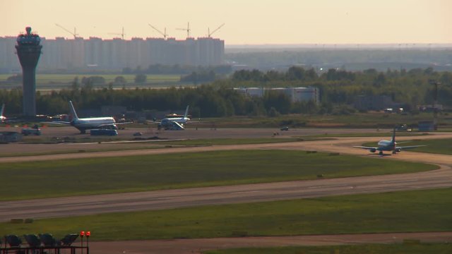 Infrastructure of the airport with dispatching tower, runways, technical vehicles and aircraft. View through the hot air from the ground