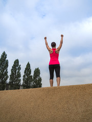 triumphant Fitness WOMAN standing IN YES POSE and making fists after workout