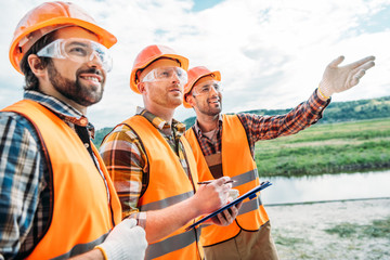 group of builders in hard hats and reflective vests pointing somewhere