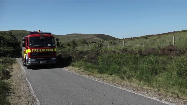 UK June 2018 - A fire truck drives along a narrow country road on a hot summer day.