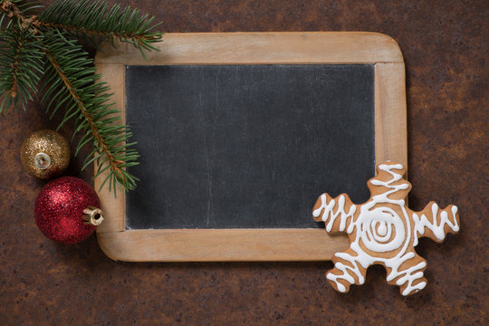 Christmas decoration. Blackboard and gingerbread Snowflake, spruce twig and Christmas tree balls. Empty space for text.