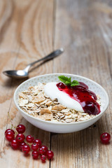 Rote Grütze Müsli mit Joghurt und Haferflocken auf Holzuntergrund