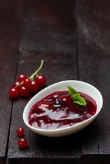 Rote Grütze mit Johannisbeeren in einer Schale auf Holzuntergrund