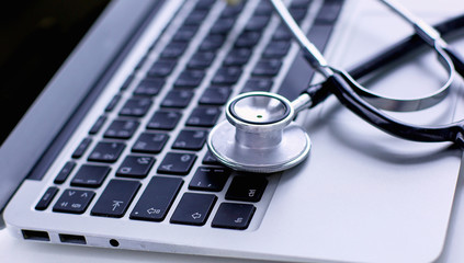 Stethoscope lying on a laptop keyboard in a concept of online m