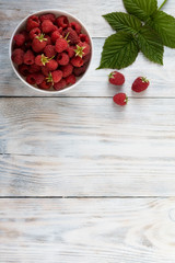 Raspberry in a bowl on a white wooden backgrond with copy space