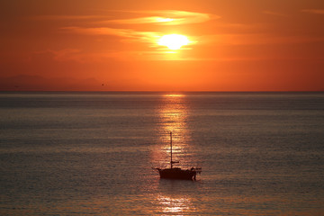 Naklejka na ściany i meble Ship in the sea on the sunrise near the coast