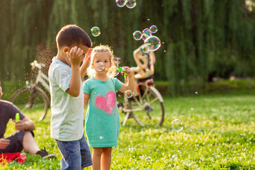 Cheerful children chase bubbles in nature.