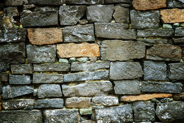 An ancient wall of stones of different sizes, vintage close-up.