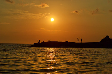 Fototapeta na wymiar People's silhouettes at beach on sunset