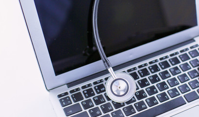 Stethoscope lying on a laptop keyboard in a concept of online m