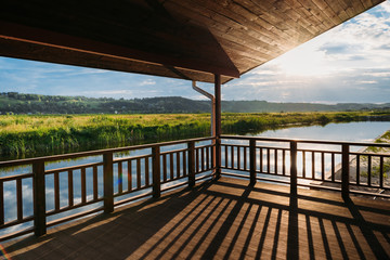view of scenic sunset over river from wooden terrace