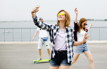 Young happy girl in hipster making selfie on phone