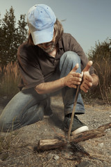Man in hat successfully made a fire with wood stick friction