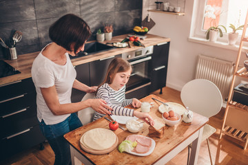 Mother serving breakfast to her daughter - obrazy, fototapety, plakaty