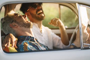 Cheerful gay couple reading map in car