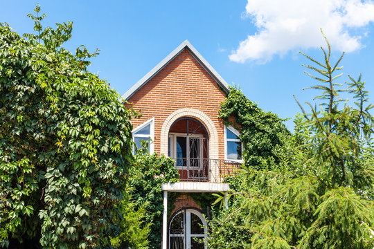 facade of country brick house and green trees