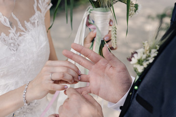 bride puts ring on groom's hand close-up
