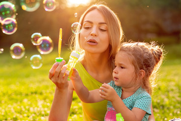 family, happiness, childhood and people concept - Female child blows soup foam and make bubbles...