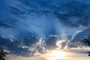Naklejka premium dark blue rainy clouds over sundown sun