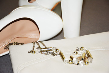 White handbag combined with white shoes on grey background