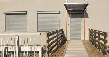 Metal blinds on the doors and windows of the facade of the house