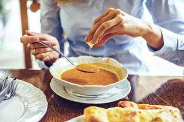 Woman squishing lemon in green peas soup