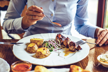 Woman eating skewers with potatoes and vegetables