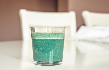 Spirulina shake in a glass on white table