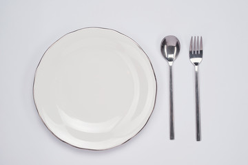 Dinner plate setting top view. Empty plate and silverware set on wooden table
