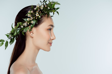 profile portrait of naked asian girl in floral wreath, isolated on grey