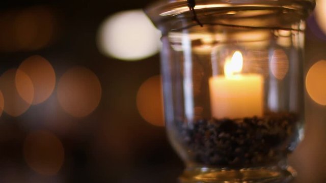 Candle flickers in glass, bokeh in background