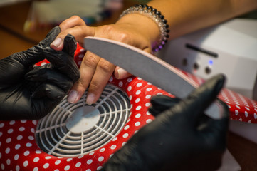 Obraz premium The master of nail extensions makes a hardware manicure and covers the nails with gel varnish in the beauty salon
