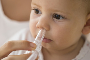 mother cleaning babies nose. nasal aspiration connected to vaccum cleaner