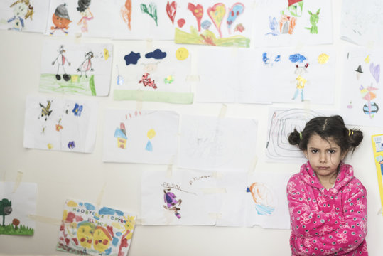 Little girl sad and angry in her bedroom with her draws in wall