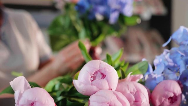 Florist girl makes a bouquet in a flower salon, close-up