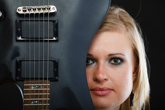 Blonde woman holding electric guitar, black background