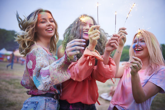 Three women holding sparklers at music festival