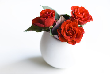 Fototapeta premium Red roses/white vase on a white background with three red roses.