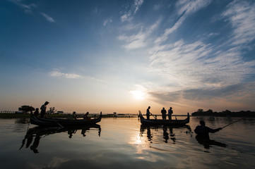 Obraz na płótnie Canvas Boats with tourists on the Taung Tha Man Lake with the U Bein Bridge in the background during a sunset in Mandalay, Myanmar