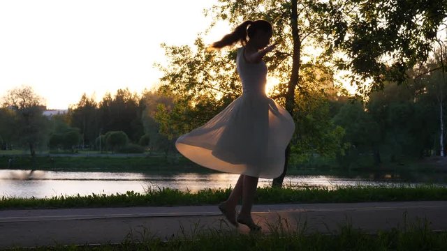 Happy woman dancing in park at sunset